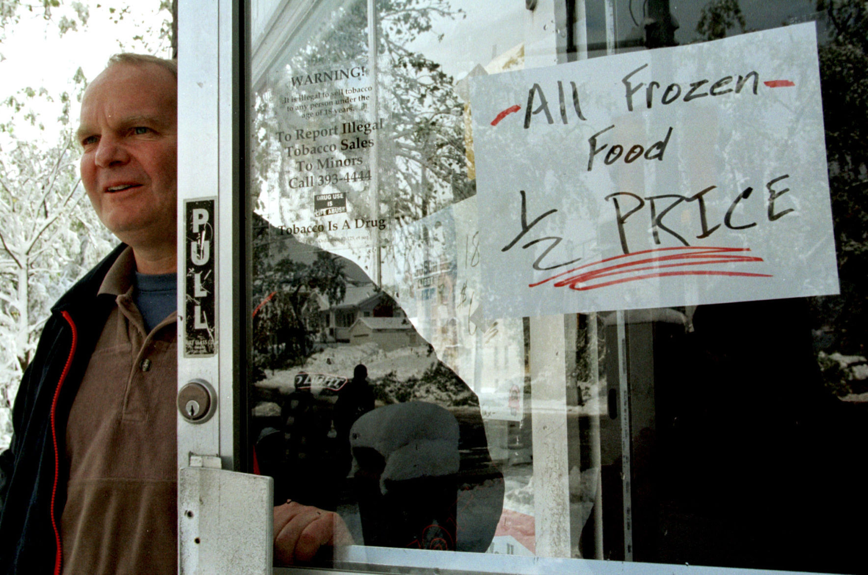 Bob Fields, owner of Mike's grocery Store, stands outside to let motorists know he is open.